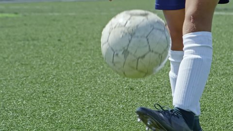 Low-section of unrecognizable boy in soccer sneakers and knee high socks juggling ball on green grass of playing field Video Stok
