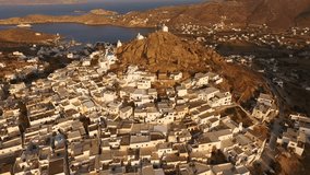 Aerial bird's eye view video taken by drone of beautiful chora churches in Ios island at sunset, Cyclades, Greece