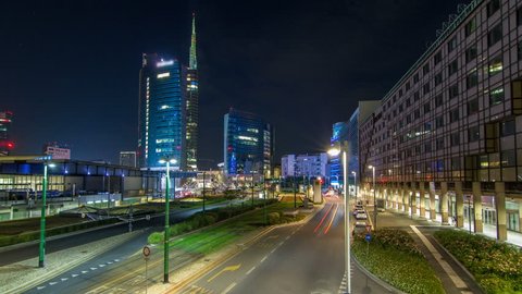 Milan skyline with modern skyscrapers in Porta Nuova business district night timelapse in Milan, Italy. Traffic on the road. Light in windows. Top view from bridge