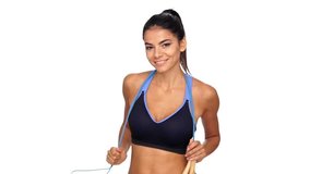Happy brunette fitness woman posing with jumping rope and looking at the camera over white background