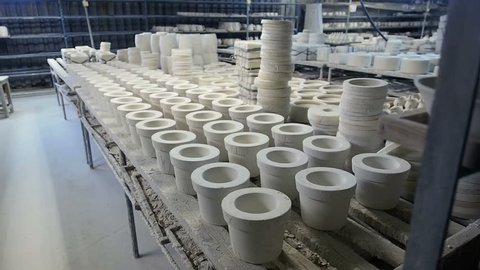Porcelain cup and dish making. Crockery Production. Porcelain cups production. Porcelain, china or fine china factory.  Pottery on shelves at a ceramist's studio.
