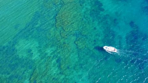 Aerial view video taken by drone of boat cruising in Caribbean tropical beach with turquoise - sapphire waters