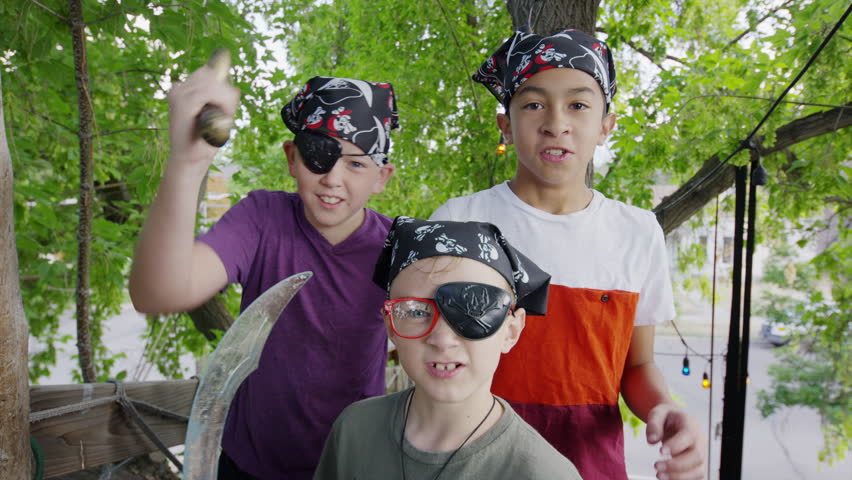 Close up of boys holding swords playing pirate in tree / Provo, Utah, United States