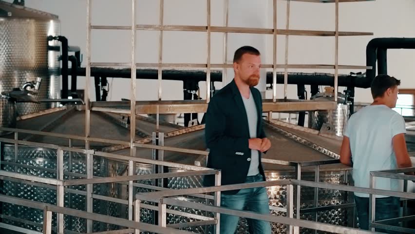 Man vintner and winemaker inspecting equipment for production and distillation wine at factory. Business owner checking equipment for fermentation at wine production
