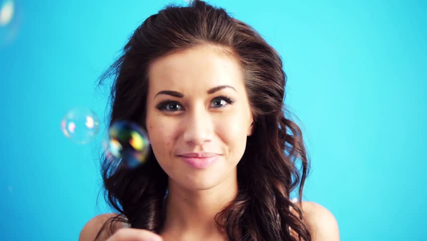 young woman blowing bubbles to the camera