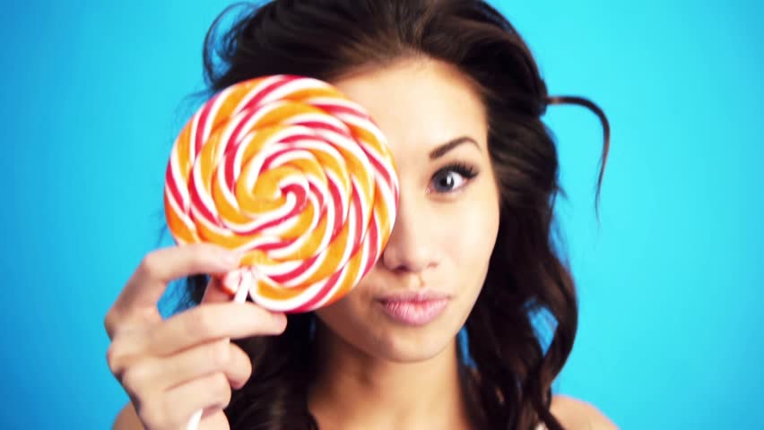 woman witn a lollipop smiling and sending kiss