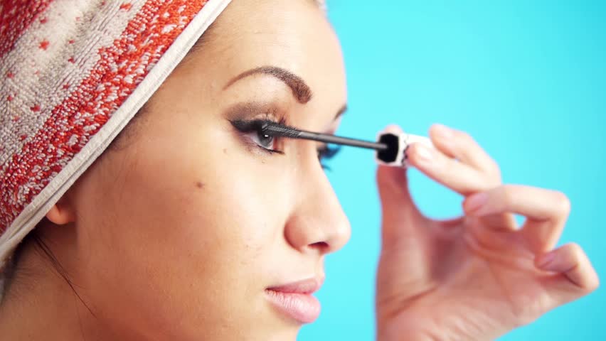 woman putting on mascara on her eyelashes