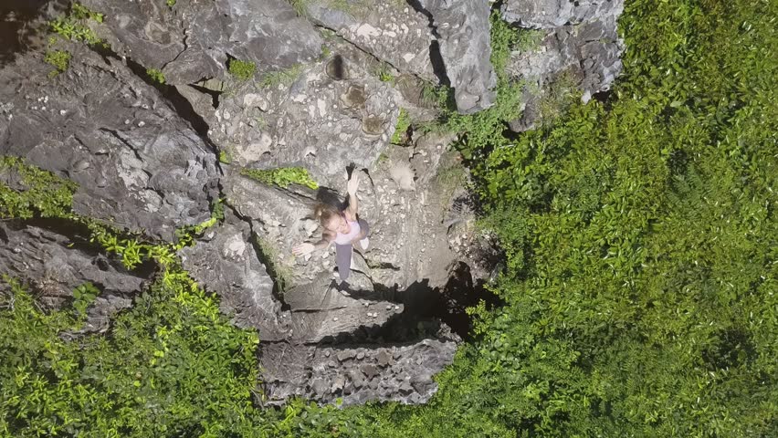 camera moves up from girl waving hands among steep cliffs covered with wild jungle and village aside