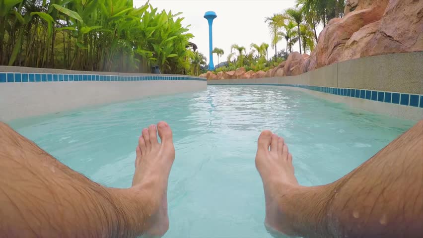 Young Happy Man Having Fun in Water Park on Rubber Donut Ring. Feet Dancing in Swimming Pool. Pattaya, Thailand.