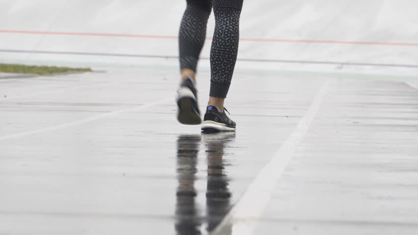 Young motivated woman runner walking outdoor at the track