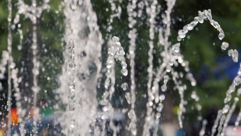 Water jet slow motion. Water drops and splashes fly in an air. City park fountain working, slow mo footage