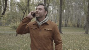 Man speaking smartphone walking on autumn forest park Full HD video. Young male calling mobile phone device