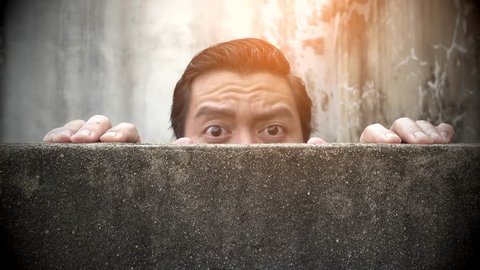 Asian men climb up concrete walls appearing suspiciously