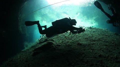 Cave divers swimming in undeground passages. Cenote underwater diving in Mexico.