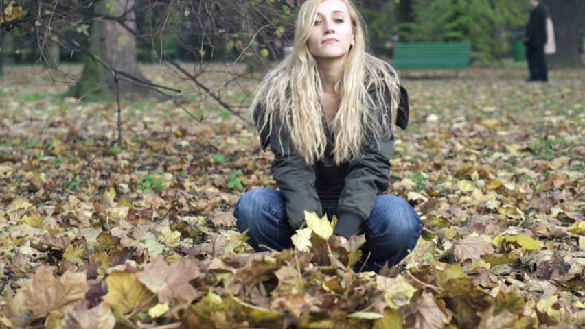 Woman throwing golden leaves in autumn park
