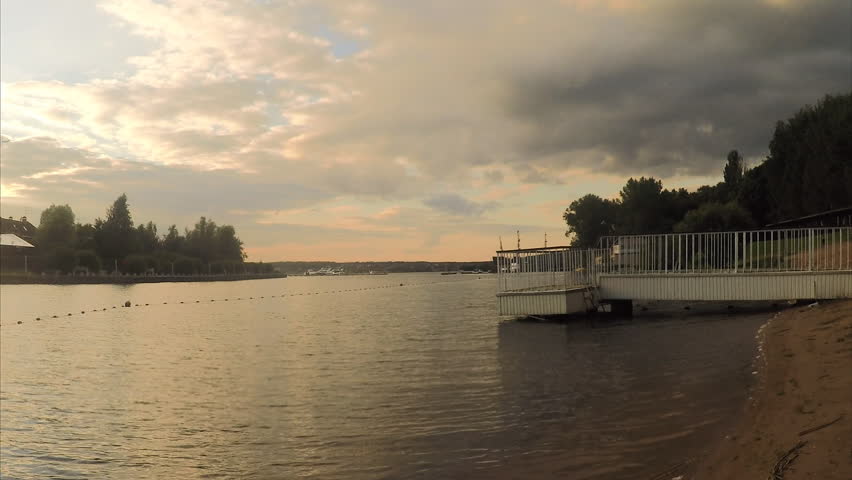 pier on the sandy shore of a pond at sunset