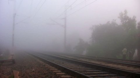 BANGALORE, KARNATAKA, INDIA - DEC 12, 2007. Indian passenger train passes by at high speed in the foggy winter morning in the suburbs of Bangalore, Karnataka, India.