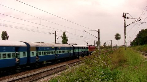 Indian passenger train passes by at high speed in the suburbs of Bangalore, Karnataka, India.