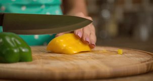 Woman hand prepares salad at home kitchen 4k close-up video. Female cooking side dish: cutting bell pepper with knife, vegetables on table. Healthy food