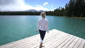 View of a young woman walking on lake pier and outstretching arms for freedom and body positive emotions. People enjoying nature in remote places concept
Shot in Jasper national park in Canada