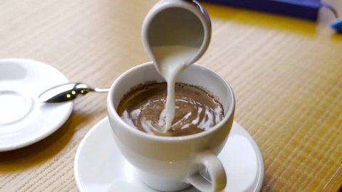 Frothed milk is poured into a cup of coffee. cappuccino preparation
