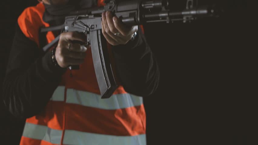 Armed man in the uniform of a worker in the dark. A criminal with a gun on a black background. Bandit at the crime scene | Shutterstock HD Video #33453580