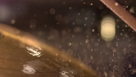Drummer hitting on wet drum cymbal, and the water splashing from cymbal in slow motion 120 fps.