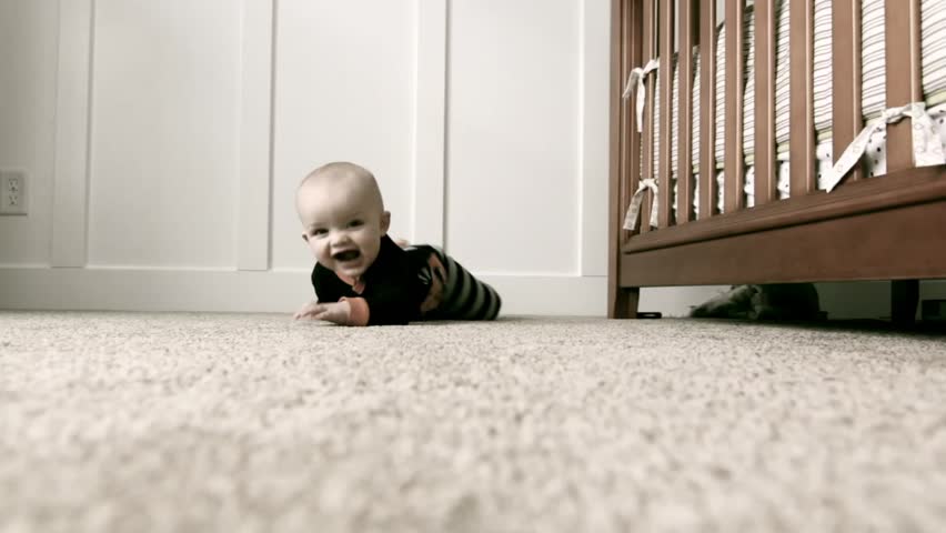 A baby playing by his crib