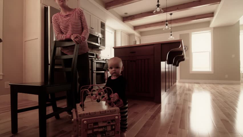 A baby playing near the kitchen