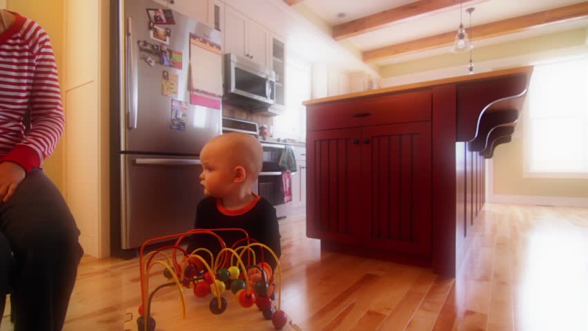 A baby playing near the kitchen