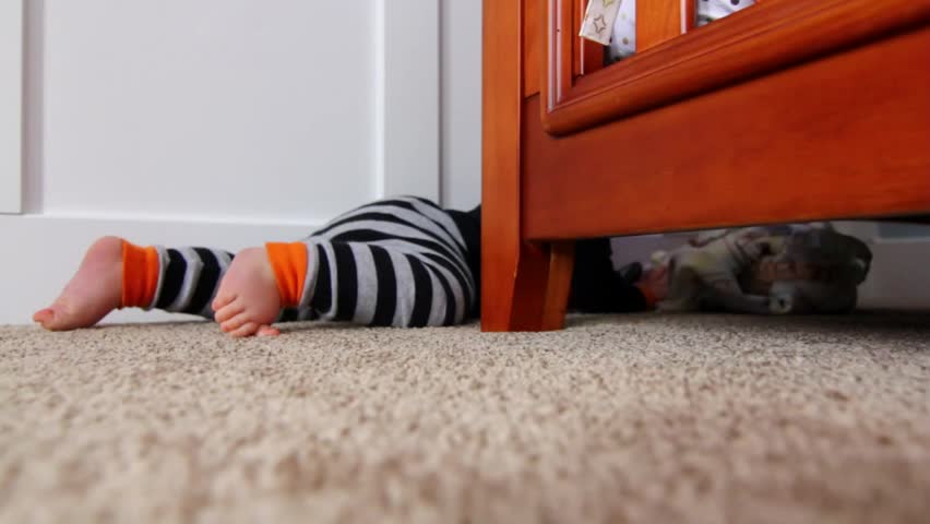 A baby playing by his crib