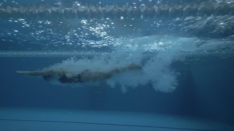 Woman swimmer dive in water pool at start slow motion. Close up female swimmer jumping in water floating pool. Underwater view swimmer jump at deep water pool 60 fps