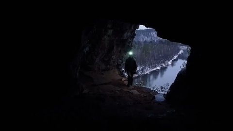 Man Silhouette Exploring a Cave. Scientists  exploring dark caves. Speleology man descent into the cave.