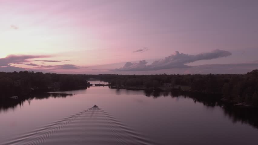 Flying following a pontoon boat heading home at sunset on lake McKellar 