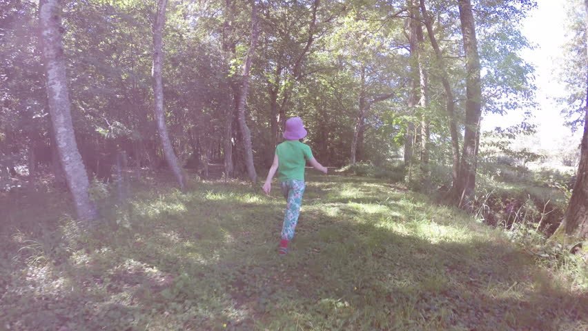 Little girl walking on green footpath. Summer lifestyle moment of a happy childhood.