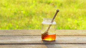 The hand hinders honey with a wooden spoon in a glass jar with honey. Slow motion, blur