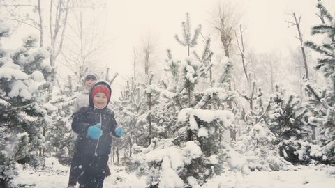 Kids are having fun running between snow trees in winter time, happiness concept