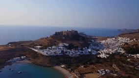 Aerial birds eye view video taken by drone of iconic medieval Acropolis and village of Lindos, Rhodes island, Dodecanese, Greece