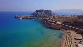 Aerial birds eye view video taken by drone of famous beach of Agathi and Feraklos castle uphill overlooking the beach, Rhodes island, Dodecanese, Greece