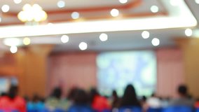 Blurred of Audience listening speaker speech in conference hall or seminar room with blur light people background.