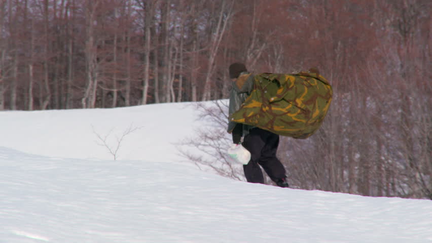 Woman carrying a heavy load on her back through the snow