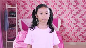 Video footage of a toothless little girl chewing bubble gum in the bedroom with pink color interior at home