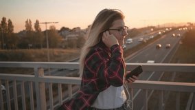 Slow motion video of attractive pretty young woman, student or teenager walk confident and happy, optimistic, dances music beat or rhythm, happy and energetic, at sunset filled street