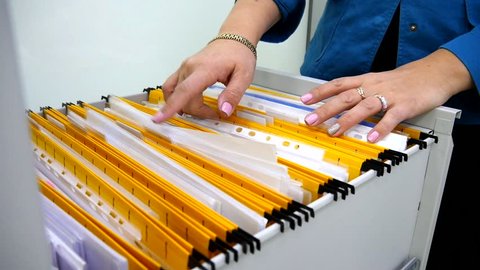 Woman hands sort folders in a drawer for papers