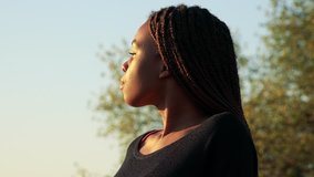 Young beautiful black woman looks around in park during sunset - closeup