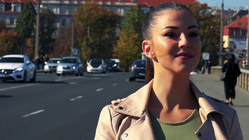 Young beautiful woman looks around in the city - street in the background