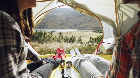 Young couple sitting inside a tent in mountains