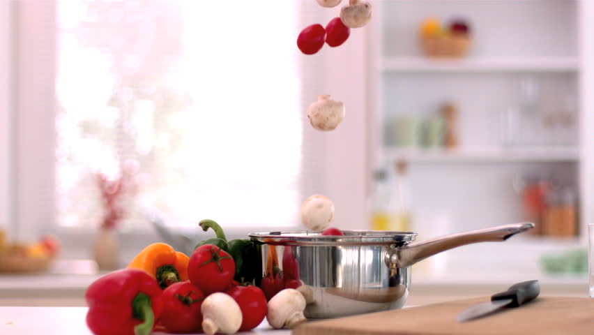 Cherry tomatoes and mushrooms falling in saucepan in kitchen in slow motion - Powered by Shutterstock - Get 15% off with code: PIKWIZARD15