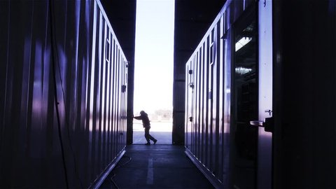 Man Opening the Door of a Container Warehouse. View from Inside. 