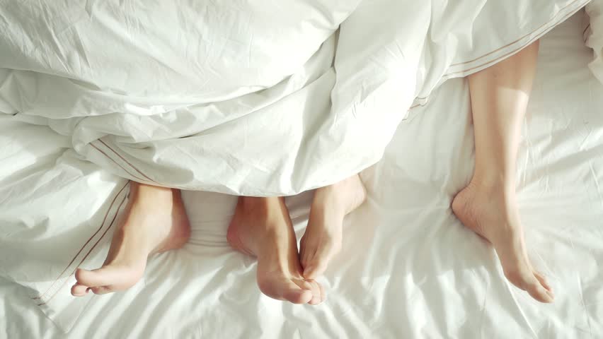 Couple in bed making love. male and female legs top view, white linens. sex, 4k